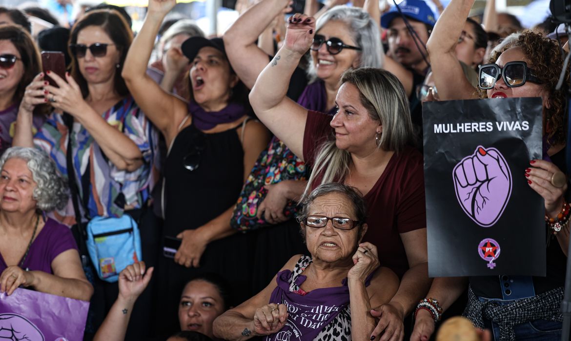 Manifestação de mulheres com cartaz escrito “Um Brasil de mulheres em ato público com cartaz preto e roxo e bandeiras.